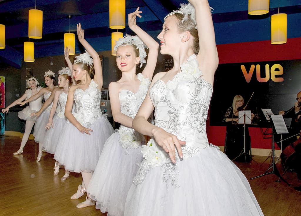 A row of young ballet dancers, with a string quartet just visible to the right
